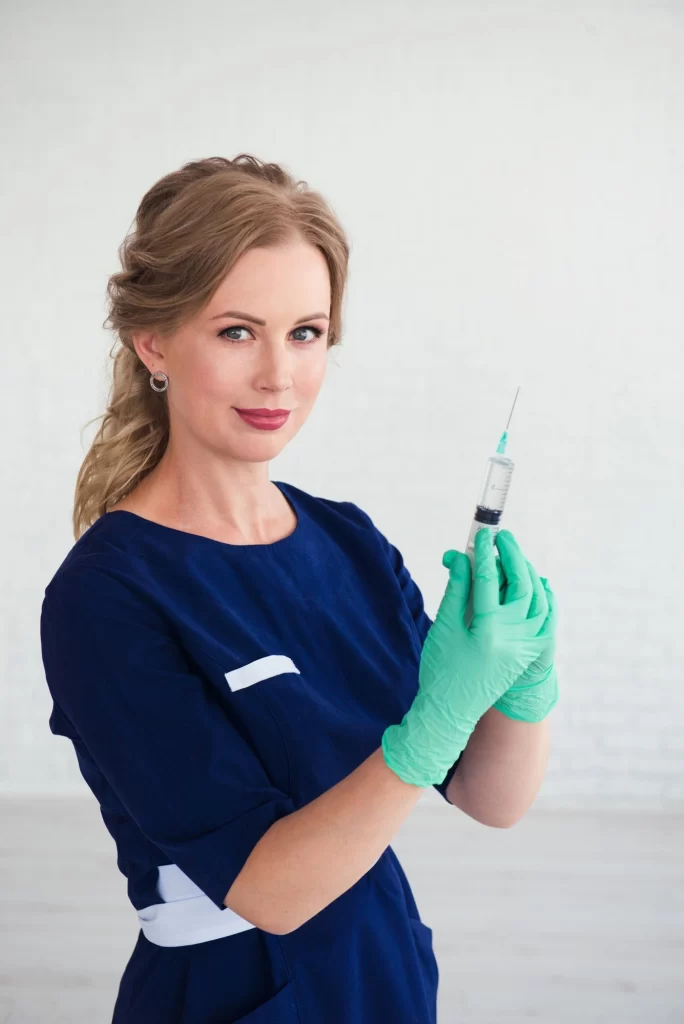 Young woman cosmetologist in blue uniform holding syringe beauty face injection