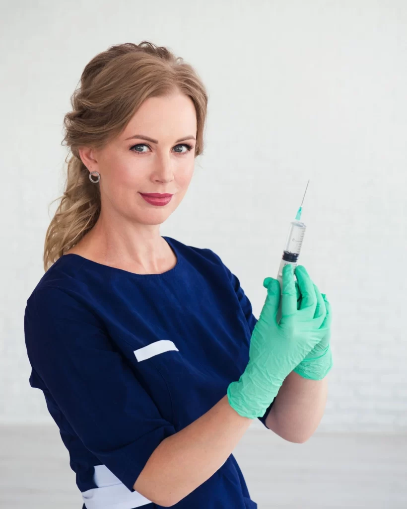 Young woman cosmetologist in blue uniform holding syringe beauty face injection